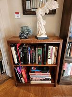 Wood bookshelf with occult and witchcraft books, showing upright condition and surface scratches