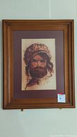 Framed original artwork depicting a bearded man in a fur hat hung on a wall.