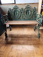 Front view of bench showing ornate cast iron backrest with two oval medallions and wood slat seat