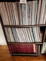 Three shelves of vinyl records on wooden shelving