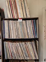 Three wooden shelves filled with vinyl LP records