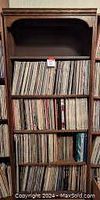 Full bookshelf with four shelves filled with vinyl LP records tightly packed.