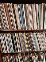 Four-tier wooden shelving unit packed with vertically aligned vinyl LP jackets.