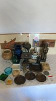 Full lot overview showing multiple vases, figurines, artwork, bust, ashtrays, and metal plates arranged on table