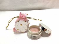 Shiseido Bio-Performance Glow Revival Cream jar open showing light pink cream with accompanying pink mesh gift bag decorated with gold stars.