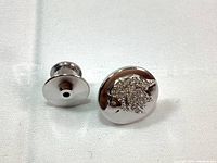 Front and back view of silver tone rhodium lapel pin with lion head design made with clear crystals.