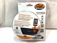 Front view of sealed Geek Squad Universal Play & Charge Solution packaging showing product compatibility and USB connection.