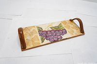 Full view of rectangular ceramic serving tray showing hand painted grape cluster and embossed leaf patterns with brown glaze handles