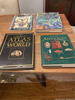 Four coffee table books laid out on a wooden table showing front covers.