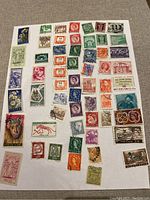 Colorful international stamps arranged on white paper showing various denominations and themes from WWII era and beyond