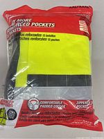 Front packaging view of Milwaukee safety vest showing high visibility yellow color, pocket count, padded collar, and zipper closure.