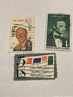 Photo showing three vintage U.S. postage stamps featuring Walt Disney, Abraham Lincoln, and the Sixth International Philatelic Exhibition