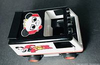 Side and top view of black, white and orange toy vehicle with Combo Panda character sticker on top and sides.