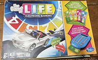 Photo of The Game of Life Electronic Banking board game box front with car piece, electronic banking unit, and cards shown.