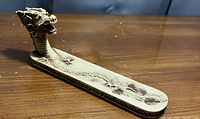 Photo of the dragon head incense holder with a textured body base and two sunburst style decorations on the tray surface.