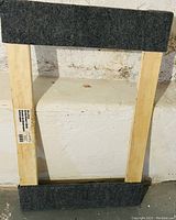 Top view of rectangular wooden mover's dolly with corners and edges wrapped in dark gray felt material for protection against damage to floors and items.