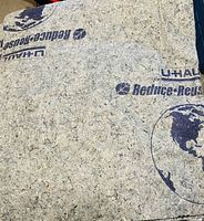 Close-up image of a brand new U-Haul moving blanket showing the texture and printed branding.