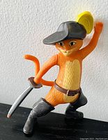 Photo of Puss in Boots toy figurine showing the front and side with sword and hat with yellow feather.