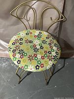 View of the retro metal framed vanity chair showing the curved backrest and floral upholstered round seat.