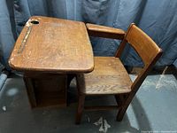Front view of solid wood vintage school desk showing attached chair and storage compartment under desktop.