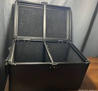 Open black storage box showing two interior compartments divided by a partition, lined with felt-like material.