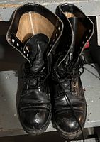 Pair of black steel toe work boots viewed from the top showing lace arrangement, scuffing, and boot interior.