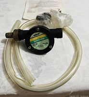 Wolfcraft drill pump overall with clear tubing and instruction sheet in background, white fabric surface.