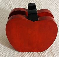 Photo of red wooden apple-shaped item with central black divider, designed for holding napkins.