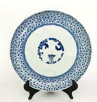 Front view of the circular blue and white porcelain plate on a black display stand