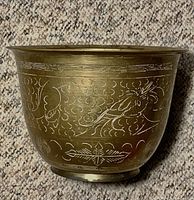 Front angle showing engraved floral and abstract designs on bronze surface