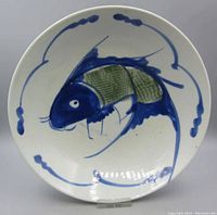 Full front view of round antique Chinese porcelain plate with blue and green fish design underglaze painted on white.