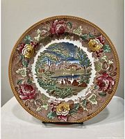 Front view of Wedgwood dinner plate showing detailed multicolor landscape with floral border.