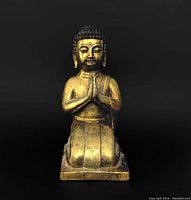 Front view of kneeling Buddha statue.