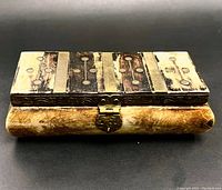 Top side view of the trinket box showing carved bone and metal inlay with decorative circular holes and metal strips.
