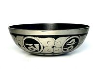 Side profile of the vintage Tibetan singing bowl showing engraved symbols and floral designs on the exterior surface in white copper on black background.