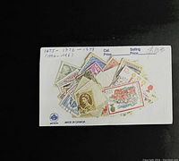 Stamps adhered to a card labeled with catalog and selling prices, showing a mix of mint stamps including Queen Elizabeth II and floral designs.