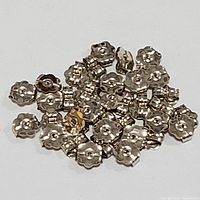 Cluster of approximately 38 small 10K white gold earring backs laid on a white surface.