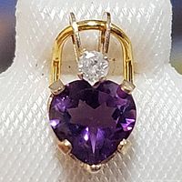 Close-up front view of heart-shaped purple amethyst pendant set in yellow gold with diamond accent above gemstone.