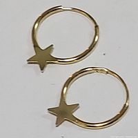 Photo showing the pair of 10K yellow gold hoop earrings with star charms, front view on a white background.