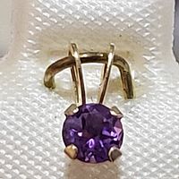 Close-up view of the 14K yellow gold pendant with a round faceted amethyst gemstone in a 4-prong setting.