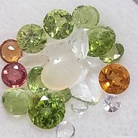 Close-up of assorted colored faceted and cabochon gemstones on a white background.