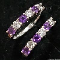Close-up photo of sterling silver earring showing five prong set stones alternating purple amethyst and clear cubic zirconia.
