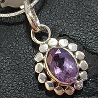 Close-up of the amethyst pendant showing the oval faceted purple stone set in a sterling silver setting with beaded border.