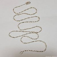 Sterling silver chain necklace laid out in a serpentine pattern showing clasp and chain details.