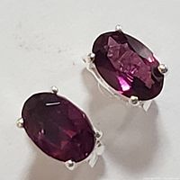Close-up photo showing the deep red oval garnet stones with four-prong sterling silver settings on earrings.
