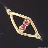 Close up of ring front showing two small rubies in an open marquise-shaped sterling silver setting with wire wrapped details on the sides.