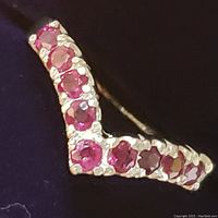 Close-up photo of sterling silver ring with multiple round rubies set in a v-shape.