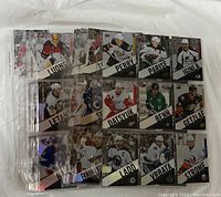 Photo of multiple hockey trading cards fanned out showing players such as Jonathan Toews, Ryan Getzlaf, Jamie Benn, and others in protective sleeves.