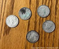 Five 1950s Canadian silver dimes showing the Bluenose sailing ship design on one side