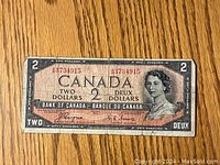 Front view of vintage Canadian $2 bill with portrait of Queen Elizabeth II and serial number.